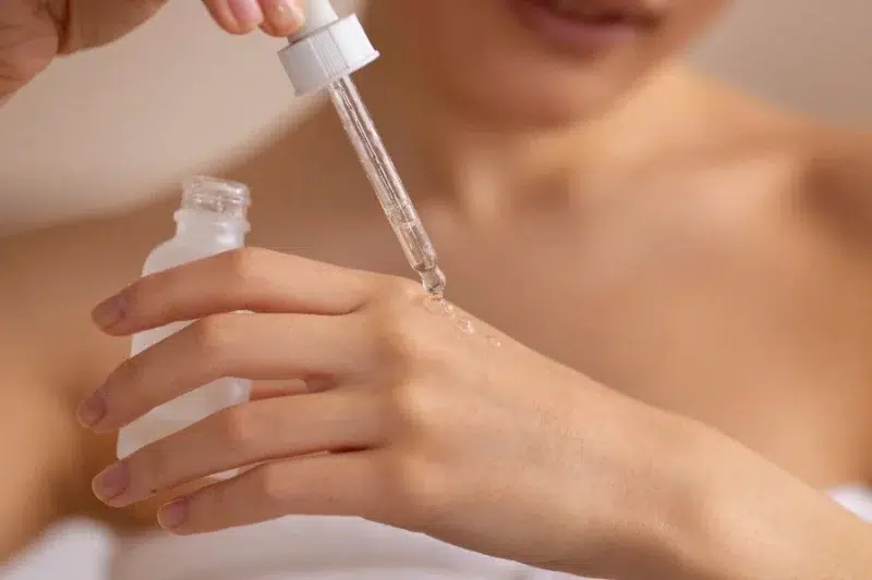 mujer aplicando crema facial mirando al espejo — errores de cuidado facial