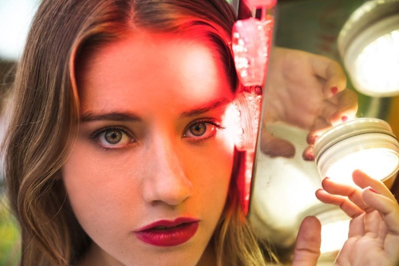 Mujer utilizando una máscara de luz LED roja para el cuidado facial en casa